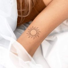 a woman's arm with a small sun tattoo on the left side of her arm