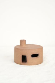 a small clay object with two holes in the center and one hole at the top