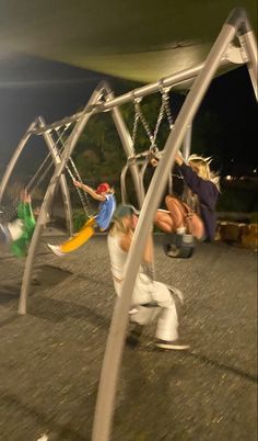 two children playing on a swing set at night