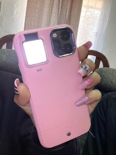 a woman holding up her pink phone case