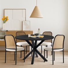 a dining room table with four chairs around it and a vase on the table next to it