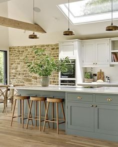 a kitchen with two stools next to an island and stone wall in the background