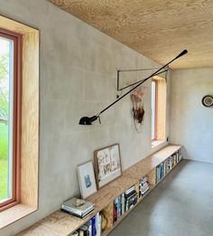 the bookshelf is full of books and pictures in front of two large windows