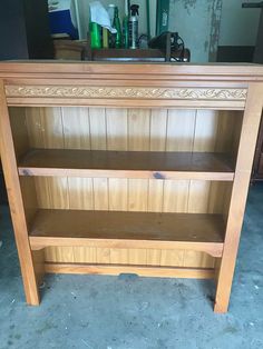 a wooden bookcase with two shelves on the bottom and one shelf below it, in front of a cabinet