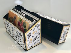 two black and white boxes with different designs on the sides, one is open to reveal an album