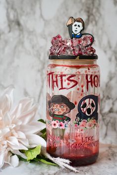 a jar with an image of a clown on it next to a flower