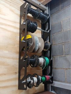 a rack with many different types of thread spools on it next to a brick wall