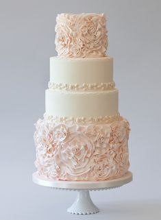 a three tiered wedding cake with white frosting and pink flowers on the top