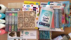 some craft supplies are laying out on a wooden table with markers, pens and glue