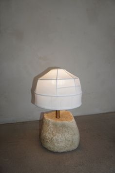 a white lamp sitting on top of a stone base with a light bulb in the middle