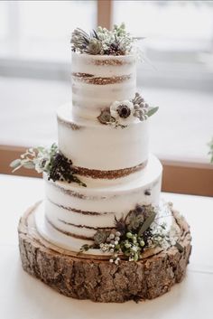 a three tiered white wedding cake with succulents and greenery on top