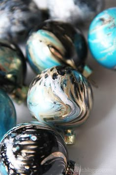 there are many different colored glass beads on the table, including one with black and blue swirls