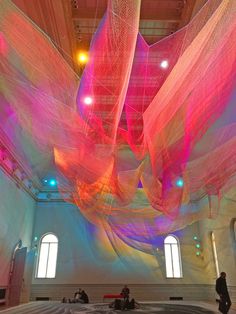 an art installation in a large building with colorful fabric hanging from the ceiling