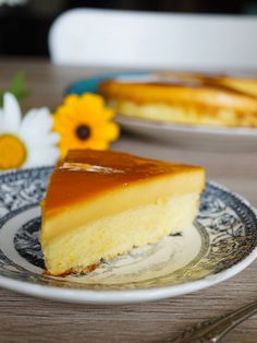 a piece of cheesecake sitting on top of a white and blue plate next to flowers