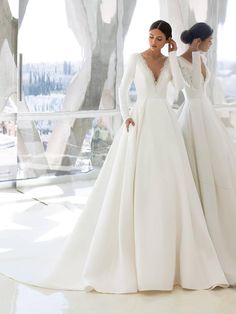 two women in wedding gowns standing next to each other