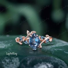 a ring with blue stones on top of a leafy green surface, in front of a blurry background