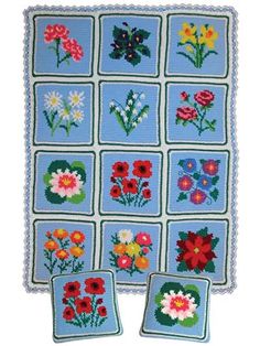 a blue crocheted blanket with flowers on it and two small square pillows in the middle