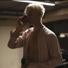 a man drinking from a cup while standing in a room