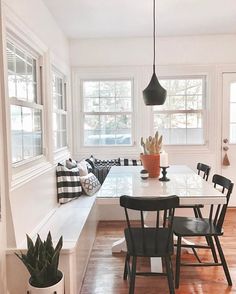 a dining room table with chairs and a bench in front of the window next to it