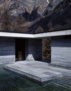 an empty pool in front of a mountain side house with mountains in the background and snow on the ground