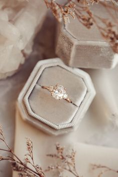 an engagement ring sitting on top of a box next to some flowers and other items