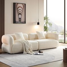 a white couch sitting on top of a wooden floor next to a large window in a living room