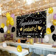 balloons and streamers are hanging from the ceiling in front of a graduation party sign