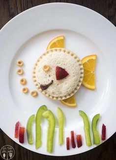 a plate that has some food on it with fruit in the shape of a fish