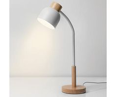 a white and wooden desk lamp with a dim light on the side, in front of a