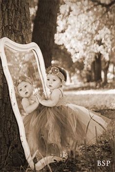 an old photo of two babies in front of a mirror