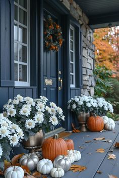 the front porch is decorated with white flowers and pumpkins