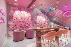 a room with pink walls and chairs in front of a table that has flowers on it