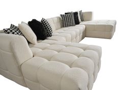 a white sectional sofa with black and white pillows on it's backrests