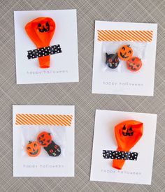 three orange and black halloween decorations in plastic bags on top of a gray tablecloth