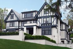 a large white house with black trim on the roof and windows, sitting on a hill