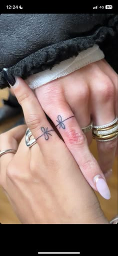 two people with tattoos on their fingers holding each other's hands and looking at the camera