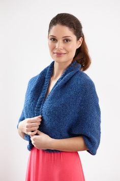 a woman in a blue shawl smiles at the camera and holds her hands together