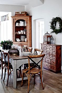 a dining room table and chairs in front of a hutch with wreaths on it