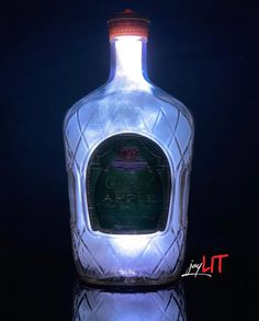 a glass bottle with a lit up label on the top is shown in front of a black background