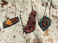 "Hand tooled and painted leather pendant necklaces to spice up that cowgirl style. The sunflower bar is on a 19\" chain. The faux turquoise painted southwest inspired pendant is on a 26\" chain. The natural freshwater pearl and classic western floral pendant is on a 24\" chain. All ready to ship and what's pictured is what you will receive." Southwestern Style Hand Tooled Necklace As Gift, Western Stamped Brown Jewelry, Western Style Stamped Brown Jewelry, Western Brown Stamped Jewelry, Artisan Brown Hand Painted Necklace, Artisan Hand Painted Brown Necklace, Handmade Western Style Necklace, Native American Headdress, Leather Pendant