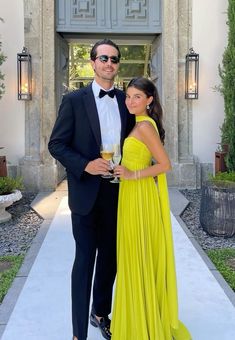 a man in a tuxedo standing next to a woman in a yellow dress