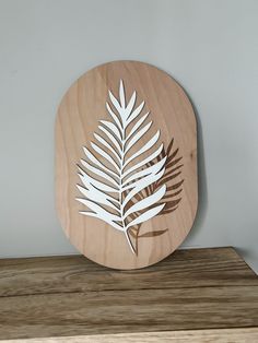 a wooden plaque with a leaf cut out on it's side, sitting on top of a table