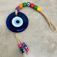 a blue plate with colorful beads and an evil eye on the front is hanging from a rope