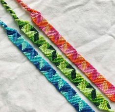 two different colored bracelets sitting next to each other on a white cloth covered surface