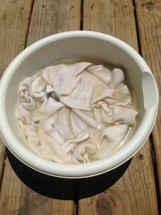 a white bowl filled with cream sitting on top of a wooden table