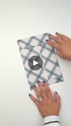 two hands holding up a piece of paper that has been folded in squares on it