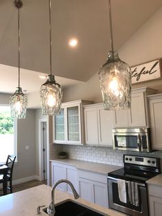 three lights hanging from the ceiling in a kitchen