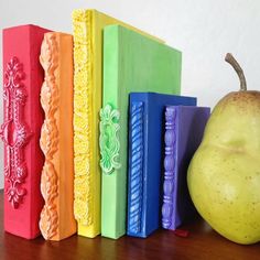 an apple sitting on top of a wooden table next to colorful books and a bookmark