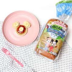 a pink plate topped with food next to a bag of organic mickey mouse waffles