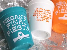 three coffee cups sitting next to each other on top of a silver tablecloth covered surface